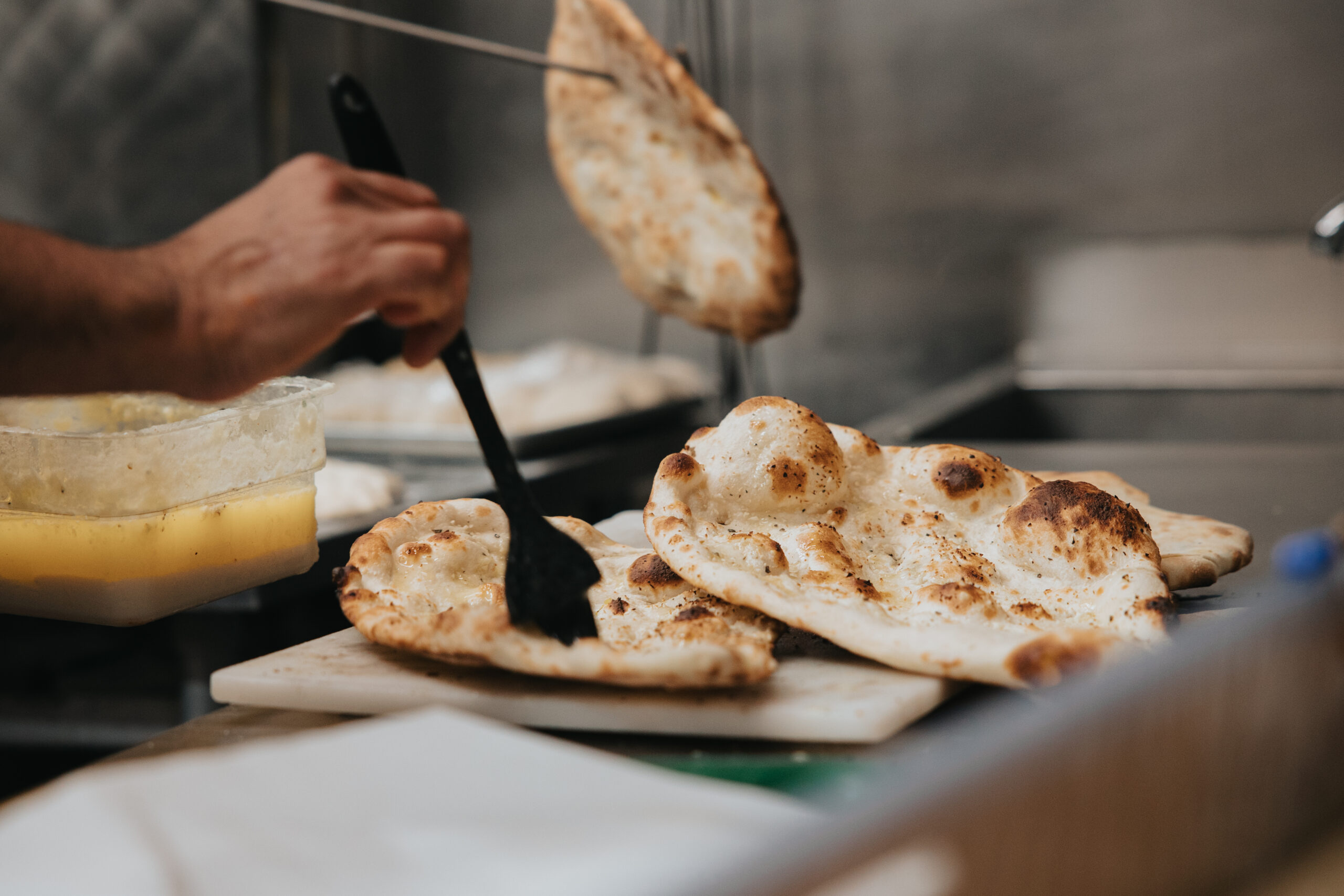 Naan dough being slapped onto the inner tandoor wall .