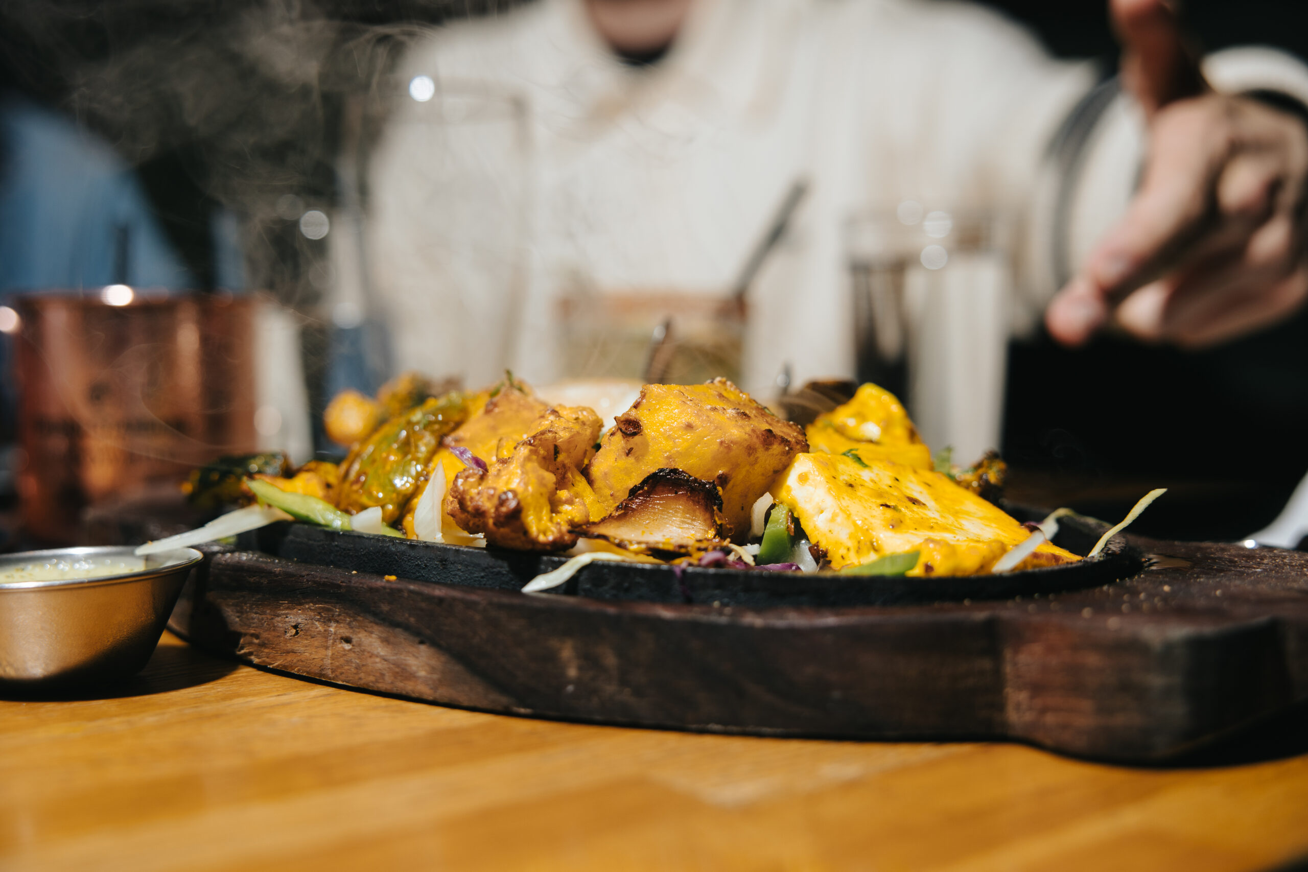 Skewers of tandoori chicken or tikka lowered into the tandoor, mid-cook .